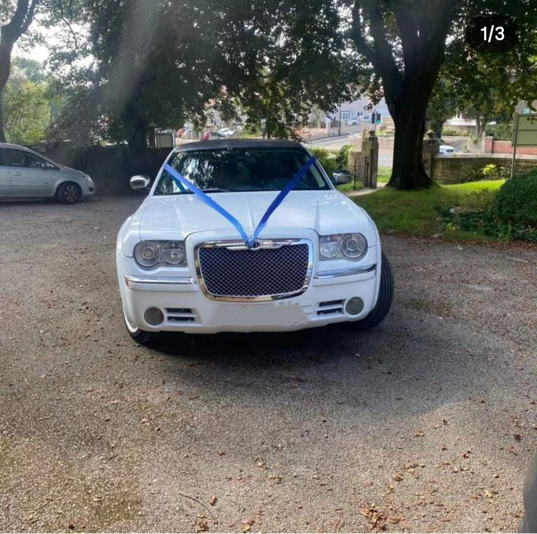 White Baby Bentley stretch limo with pink wedding ribbons outside hotel - City Limo Bradford