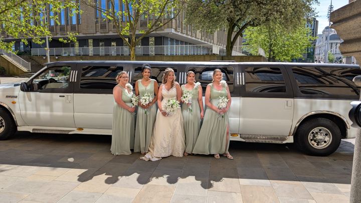 Bride and bridesmaids in sage green beside a stretch limo, Birmingham