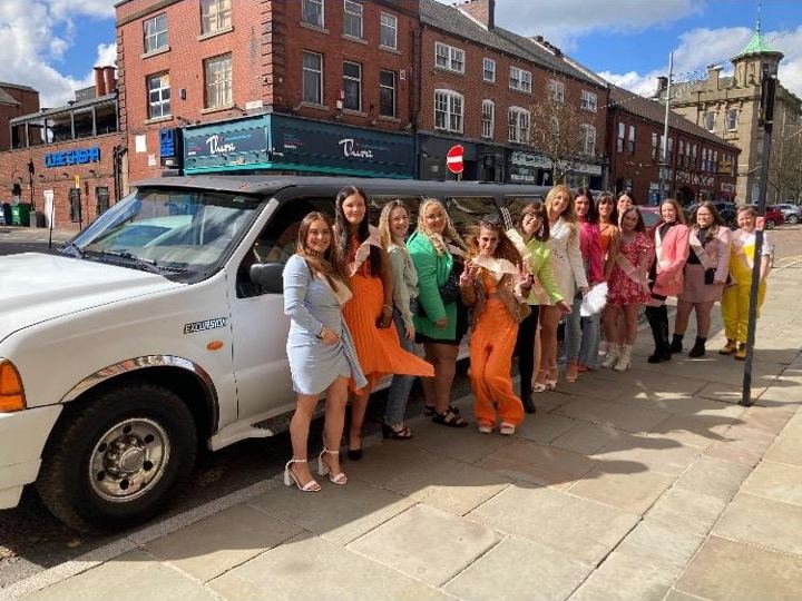 Hen party group with sashes beside a white limo, Preston