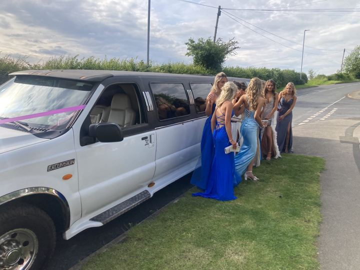 Prom girls in blue dresses beside a white limo, Rotherham